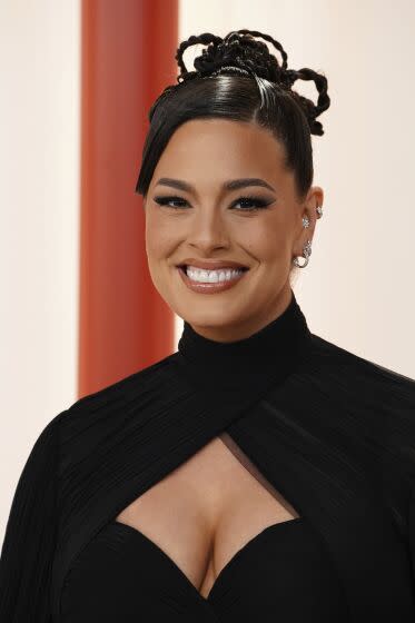 A woman with a braided bun in a black gown smiles