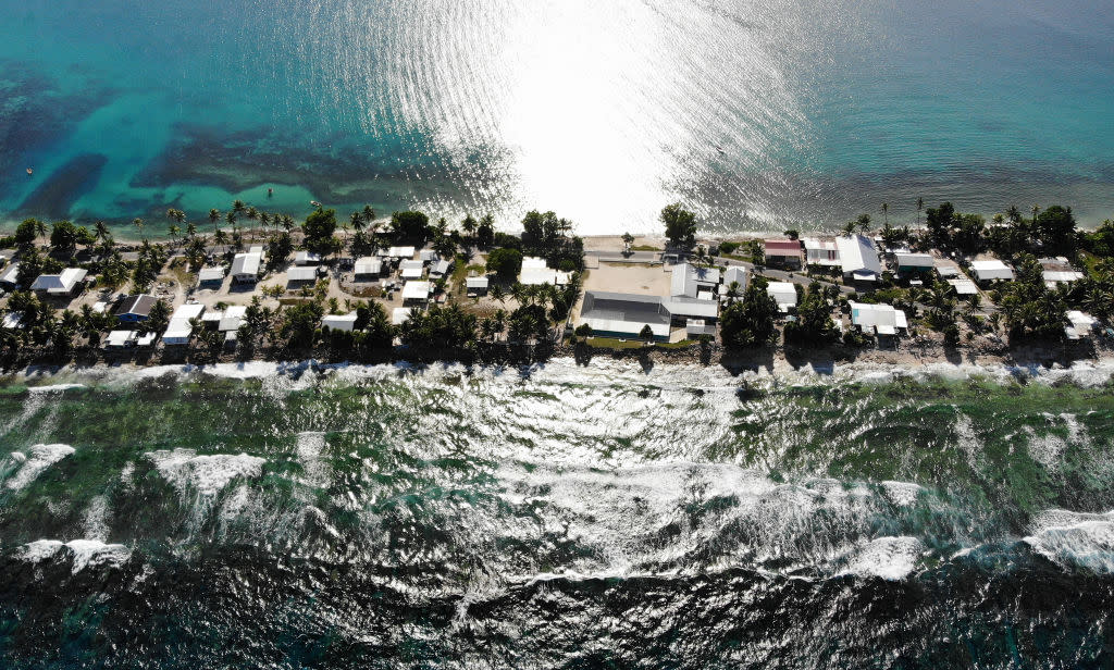  A horizontal aerial view of a thin occupied strip of land with buildings, with the ocean on each side. 