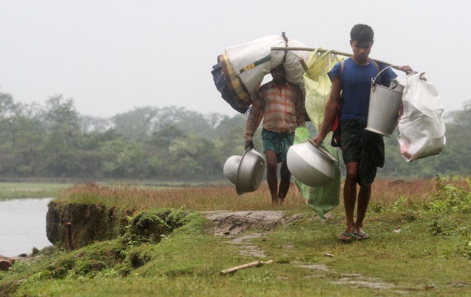 Villagers walk with their belongings along the River Beki after fleeing their violence-affected village of Khagrabari, in the northeastern Indian state of Assam, Saturday, May 3 2014. Police in India arrested 22 people after separatist rebels went on a rampage, burning homes and killing dozens of Muslims in the worst outbreak of ethnic violence in the remote northeastern region in two years, officials said Saturday. (AP Photo/Anupam Nath)