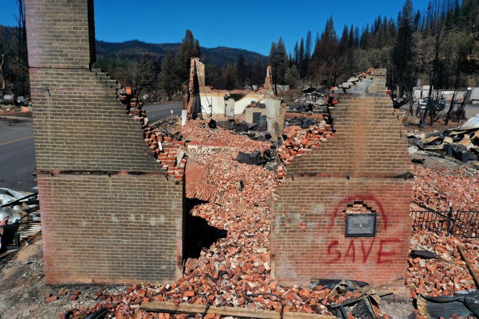 Two brick walls stand amid rubble, one with the word "save" painted on it