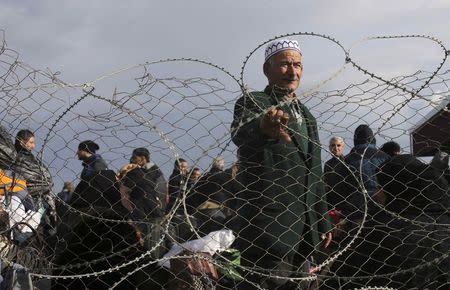 A Palestinian man, hoping to cross into Egypt, stands behind a fence as he waits at the Rafah crossing between Egypt and the southern Gaza Strip December 21, 2014. REUTERS/Ibraheem Abu Mustafa