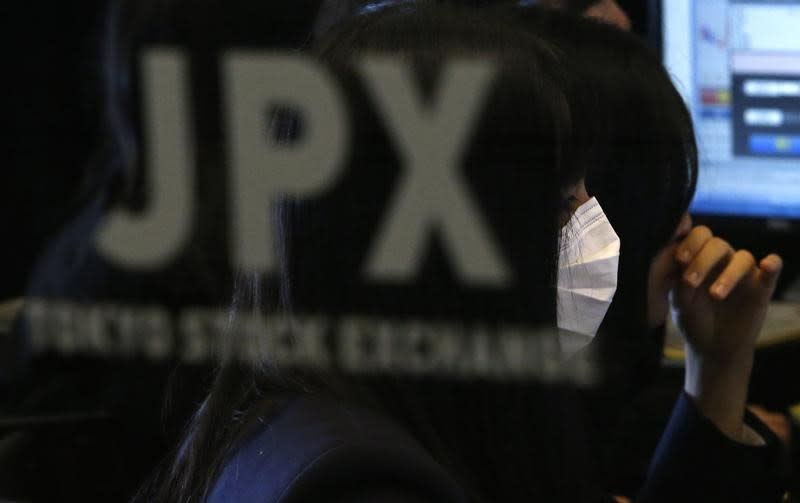 A visitor wearing a mask is seen behind a logo of Japan Stock Exchange (JPX) at the Tokyo Stock Exchange in Tokyo December 15, 2014. REUTERS/Yuya Shino