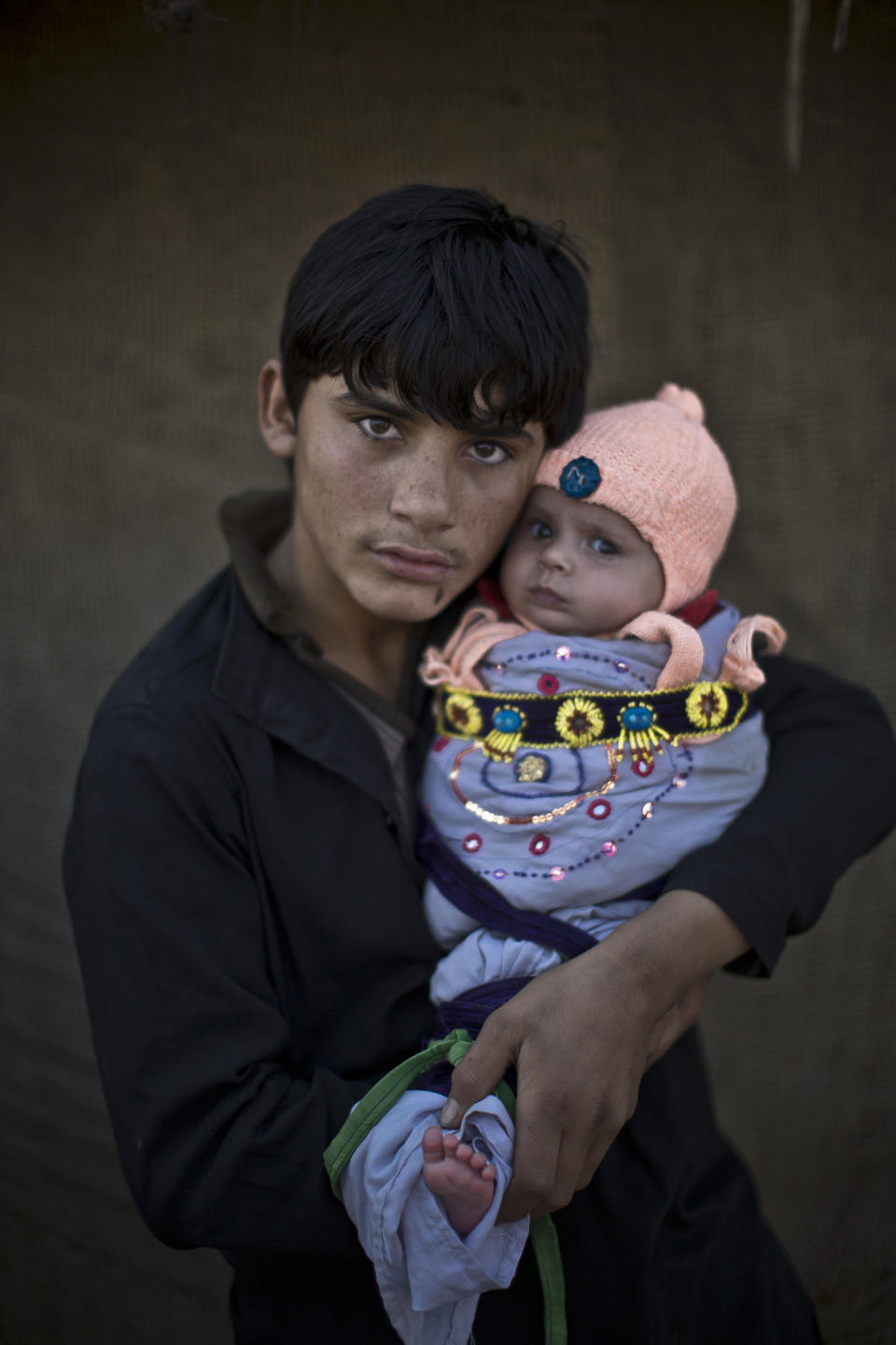 In this Saturday, Jan. 25, 2014 photo, Afghan refugee youth, Shahzada Saleem, 15, holds his nephew Satara, two months, as they pose for a picture, in a slum on the outskirts of Islamabad, Pakistan. For more than three decades, Pakistan has been home to one of the world’s largest refugee communities: hundreds of thousands of Afghans who have fled the repeated wars and fighting their country has undergone. Since the 2002 U.S.-led invasion of Afghanistan, some 3.8 million Afghans have returned to their home country, according to the U.N.’s refugee agency. (AP Photo/Muhammed Muheisen)