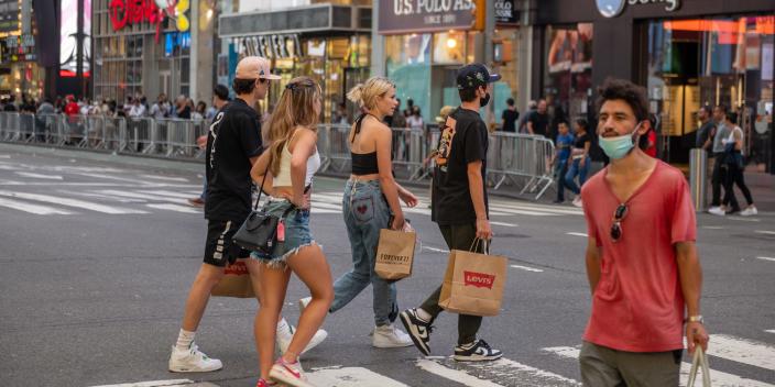 Tourists carrying shopping bags walk through Times Square in New York City.