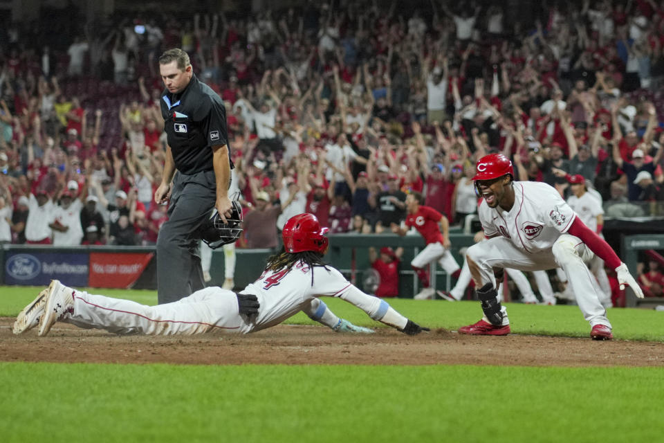 Cincinnati Reds' Elly De La Cruz, left, scores the game winning run as Will Benson celebrates during the ninth inning of a baseball game against the Seattle Mariners in Cincinnati, Tuesday, Sept. 5, 2023. (AP Photo/Aaron Doster)