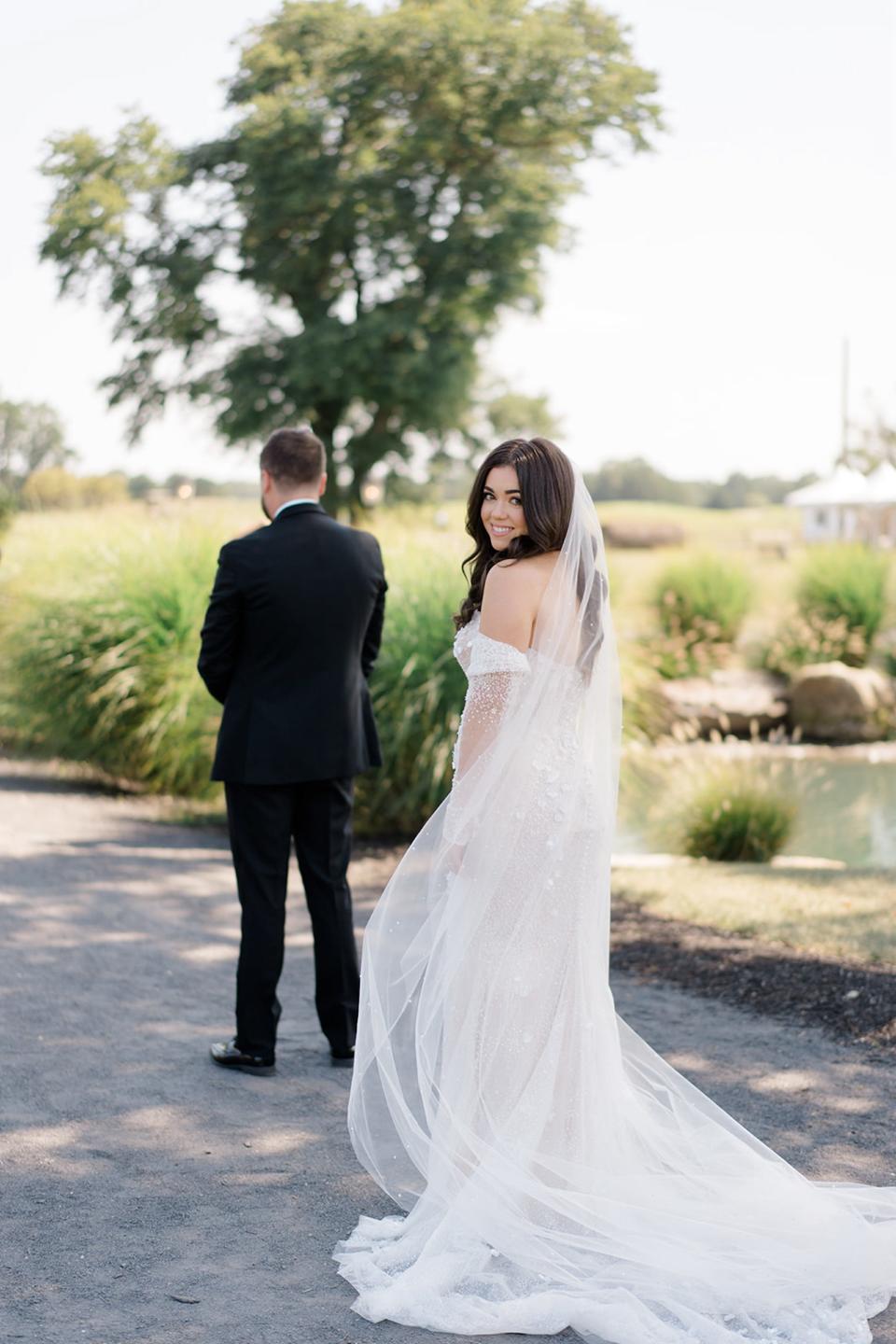 A bride looks over her shoulder as her groom has his back to her.