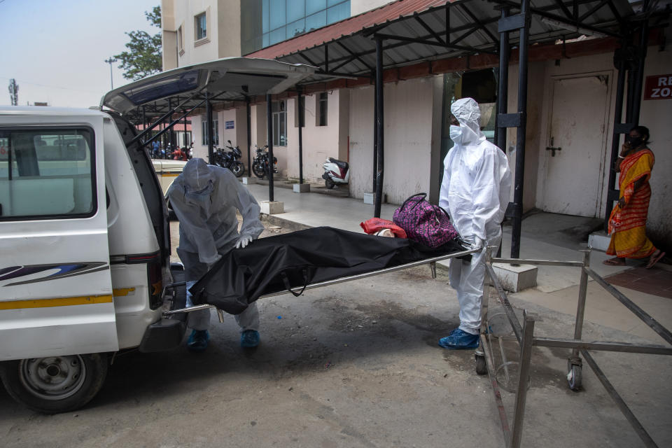 Health workers in protective suits shift the body of a COVID-19 victim at a government hospital in Gauhati, India, Monday, May 24, 2021. India crossed another grim milestone Monday of more than 300,000 people lost to the coronavirus as a devastating surge of infections appeared to be easing in big cities but was swamping the poorer countryside. (AP Photo/Anupam Nath)