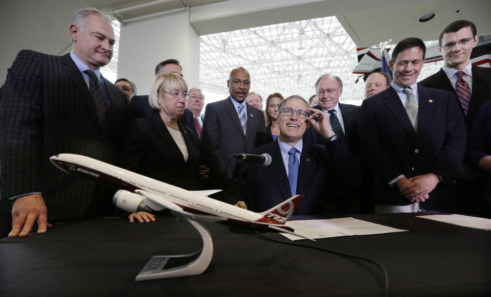 FILE -- In this Nov. 11, 2013, file photo, Gov. Jay Inslee, center, looks up during a signing event for legislation to help keep production of Boeing's new 777X airplane in Washington state, at the Museum of Flight in Seattle. Washington state lawmakers announced Wednesday, Feb. 19, 2020 that they will introduce bills, at Boeing Co.'s request, to suspend the company's preferential business and occupation tax rate until there's a final determination from World Trade Organization regarding a long-running trade dispute. (AP Photo/Elaine Thompson, File)