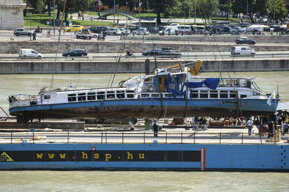 FILE - In this Tuesday, June 11, 2019 file photo, a crane places the wreckage of the sightseeing boat on a transporting barge at Margaret Bridge, the scene of the fatal boat accident in Budapest, Hungary. Hungarian prosecutors say they have charged the captain of a cruise ship involved in a May 2019 collision on the Danube River in which 28 people were killed. (Balazs Mohai/MTI via AP, file)