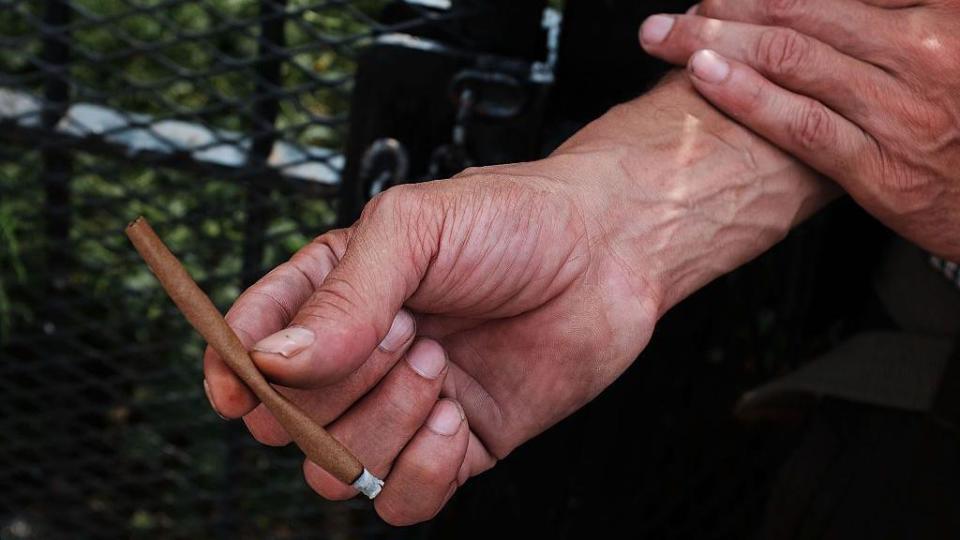 Mano de hombre sostiene un cigarrillo hecho a mano con k9