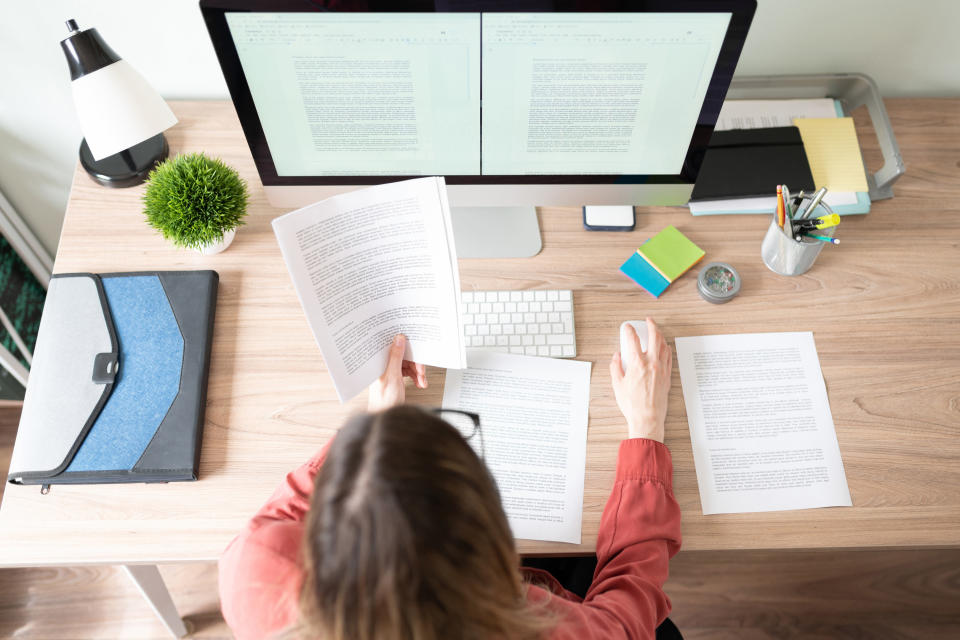 Top view of the workspace and office of a woman working on a variety of documents on the computer