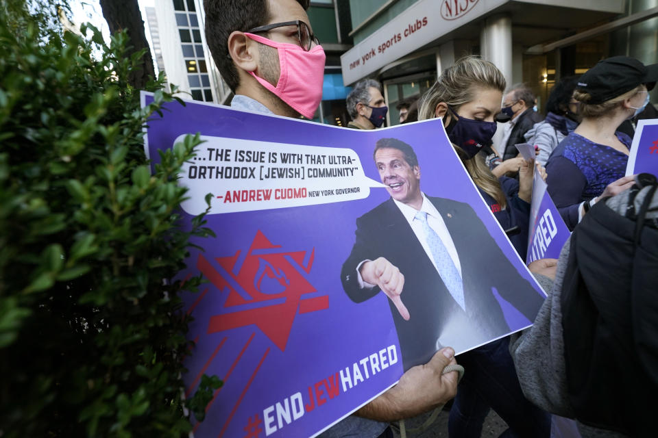 A manholds a sign as he joins protesters outside the offices of New York Gov. Andrew Cuomo, Thursday, Oct. 15, 2020, in New York. Three Rockland County Jewish congregations are suing New York state and Gov. Andrew Cuomo, saying Cuomo engaged in a "streak of anti-Semitic discrimination" with a recent crackdown on religious gatherings to reduce the state's coronavirus infection rate. (AP Photo/Kathy Willens)