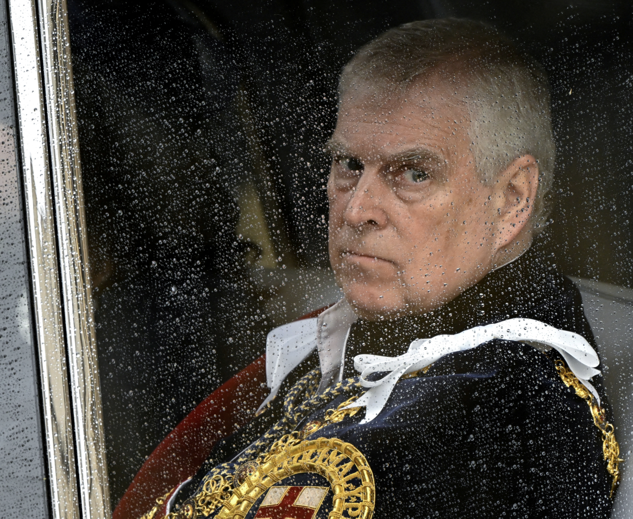 Prince Andrew seen through water-droplet covered window.