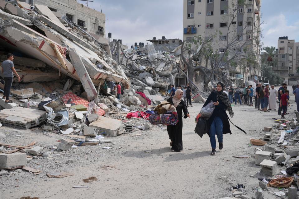 Palestinian women walk by buildings destroyed in Israeli airstrikes in Nuseirat camp in the central Gaza Strip (Copyright 2023 The Associated Press. All rights reserved.)