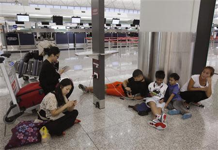 South Korea, Philippines and Poland passengers whose flights are cancelled in anticipation to typhoon Usagi, charge their mobile devices at Hong Kong International Airport