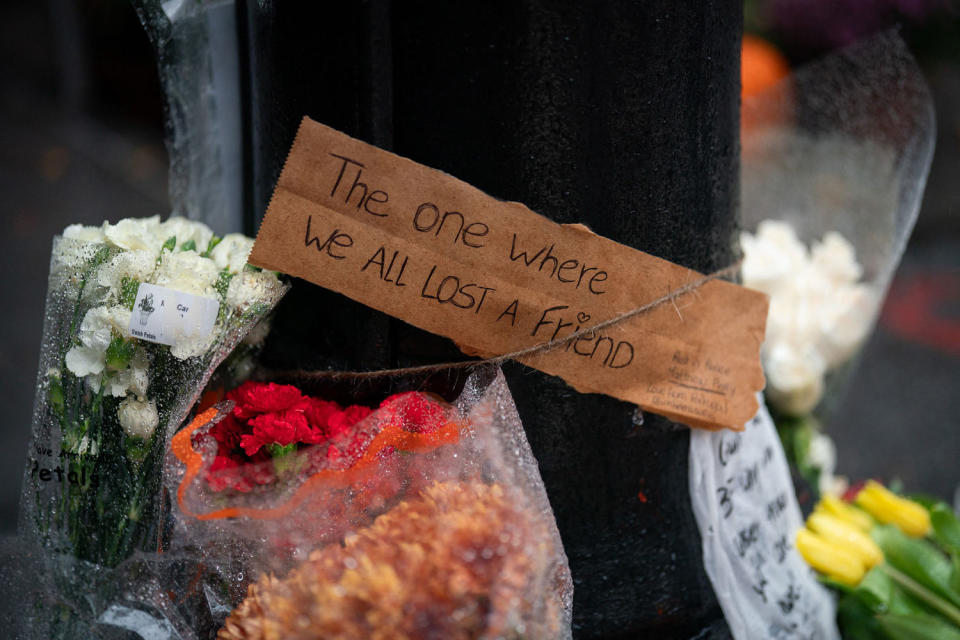 Image: A condolence sign surrounded by flowers reads 