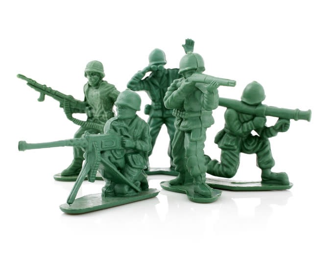 Five small green plastic toy soldiers in action poses holding weapons, including rifles and bazookas