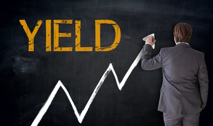 Businessman drawing a line going up on a chalkboard beneath the word yield.