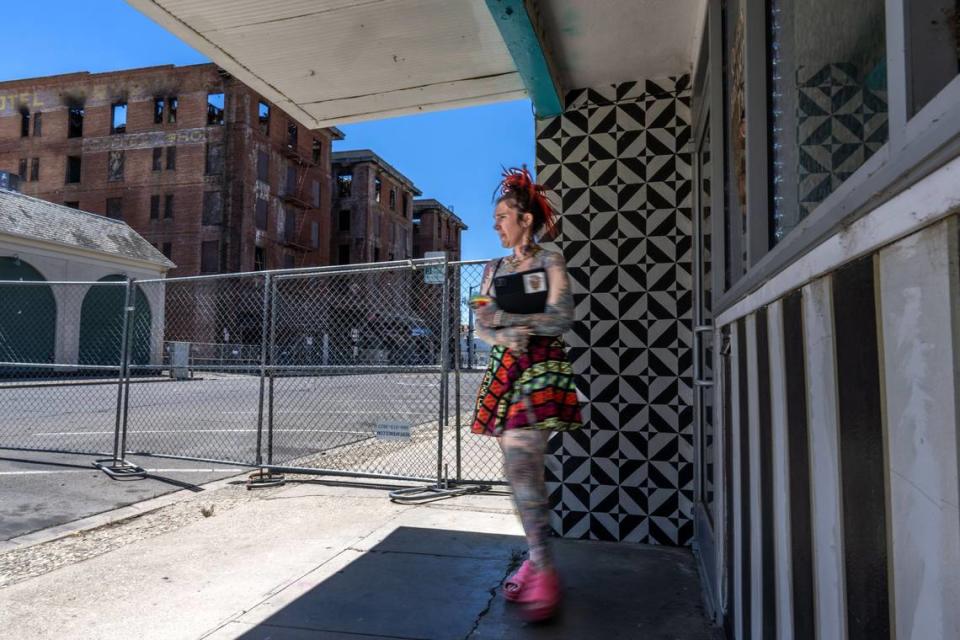 Kailey Bond, owner of Queen of Hearts Tattoo and Piercings in Marysville, walks out of her business Monday located near the burned out Hotel Marysville. Bond said the closure of streets in downtown has people thinking her business is closed.