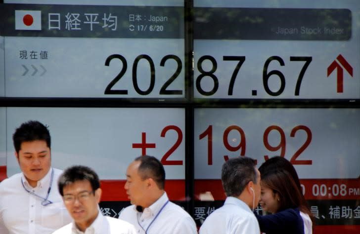 FILE PHOTO: People walk past an electronic board showing Japan's Nikkei average outside a brokerage in Tokyo, Japan June 20, 2017. REUTERS/Toru Hanai/File Photo