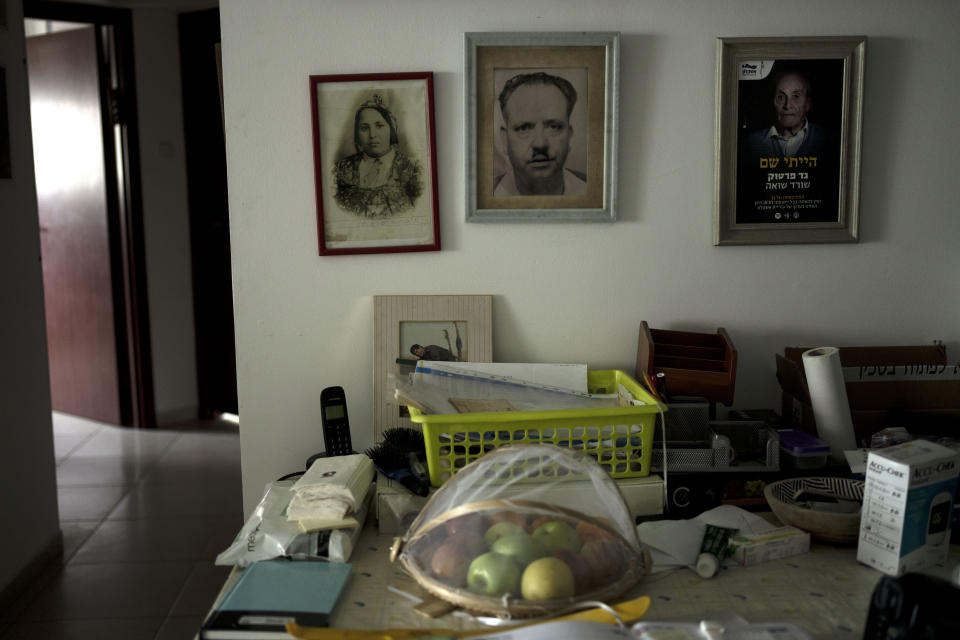 Pictures, left, of the parents of Gad Partok, 93, a Tunisian-born Holocaust survivor, are seen in the frame at right in his home in Ashkelon, southern Israel, Friday, Jan. 26, 2024. He never thought he'd have to relive the horrors of the Nazi onslaught that claimed the lives of his community members. Then, on Oct. 7, he watched on TV from his living room as Israeli news channels played videos of Hamas militants tearing through communities just a few kilometers (miles) from where he lives. He took cover as rocket fire from Gaza pounded Ashkelon, the southern Israeli city he moved to after emigrating from Tunisia in 1947. (AP Photo/Maya Alleruzzo)