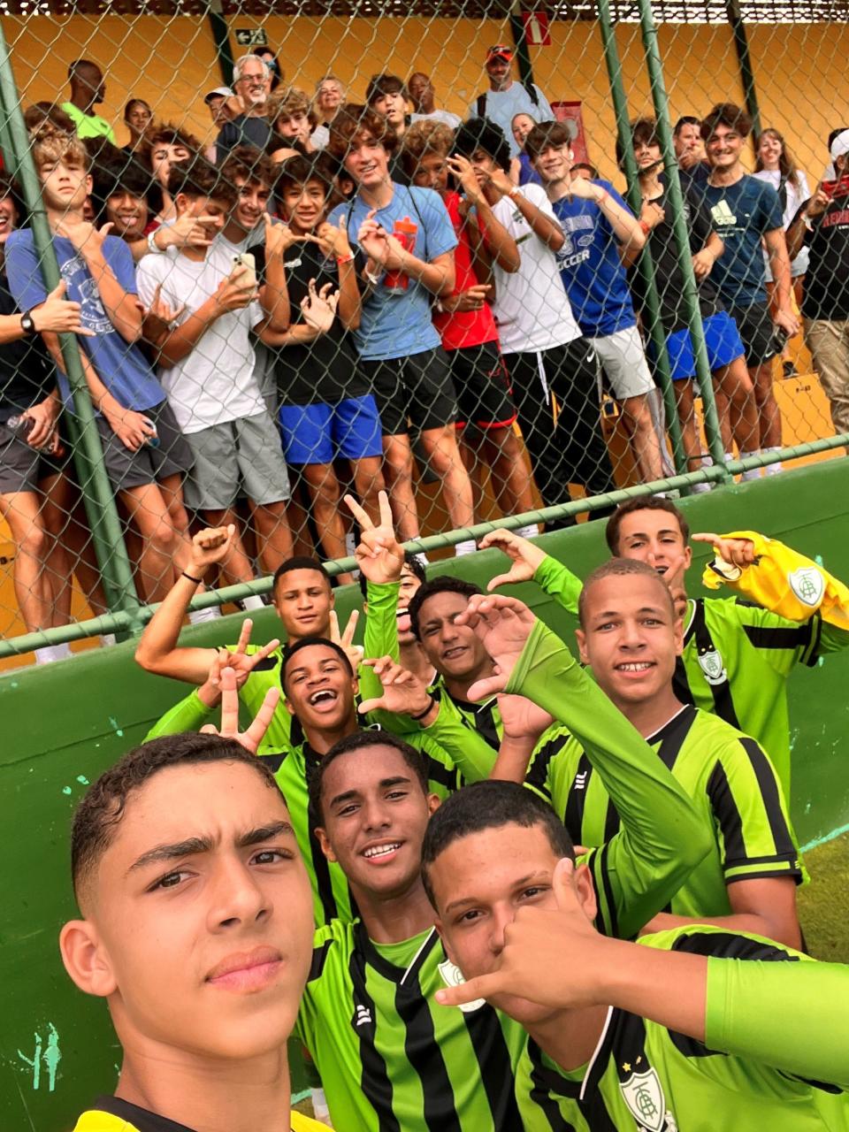 The Booker T. Washington boys soccer team (back) supports a local academy team during its game while in Brazil over Thanksgiving break during "The Brazilian Soccer Experience."