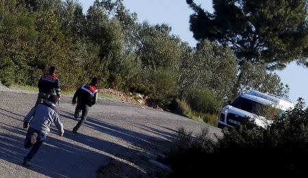 Three Turkish Gendarme officers run after a suspicious car which is believed to be owned by smugglers on a main road near a beach in the western Turkish coastal town of Dikili, Turkey, March 5, 2016. REUTERS/Umit Bektas