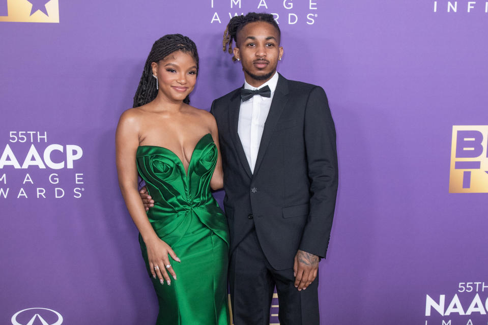 Halle Bailey and DDG on the red carpet together. Halle is wearing a strapless dress with a sweetheart neckline and DDG is wearing a tux