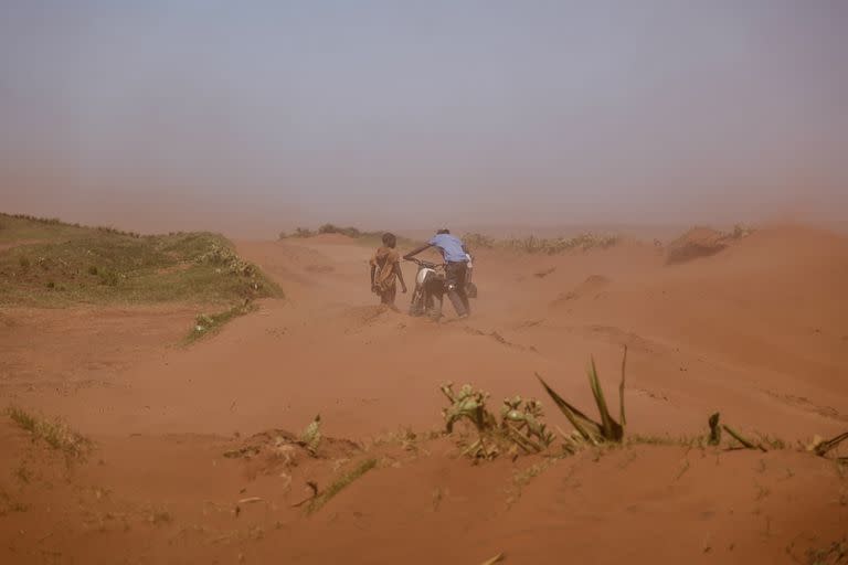 On 3 February 2022 in Ambovombe, Androy region, Madagascar, a man pushes a motorcycle through the “Tiomena” on National Road 13. This phenomenon can turn a road into a dune in just three days.

On 3 February 2022 in Ambovombe, Androy region, Madagascar, a struggling sorghum plantation during a Tiomena event.

The phenomenon called Tiomena by the locals (Clouds of dust, red wind), can turn a road into a dune in just three days, and it can be observed in its most spectacular formation in the Androy region. According to local farmers, this phenomenon has become more and more frequent since 2019.

In Southern Madagascar, Tioka is a wind that blows all year round and can create formations of dust and sand waves, it can also travel hundreds of kilometres and cover the agricultural lands of several regions like Anosy, Androy and Atsimo Andrefana. 

With a growing population, forests are often destroyed to make way for new agricultural land. The gradual disappearance of the forest leads to the denuding of the ground and increases the Tiomena's radius of action. According to a farmer, agricultural land bordered by forests is often spared by the Tiomena, but the plains are devastated.