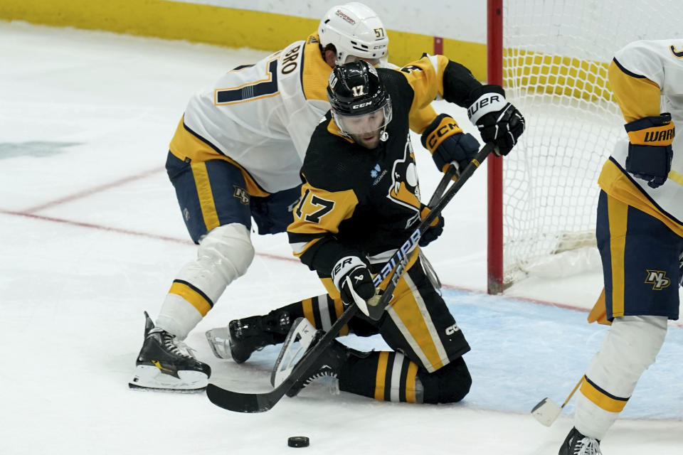 Nashville Predators' Dante Fabbro, left, and Pittsburgh Penguins' Bryan Rust (17) fight for the puck during the third period of an NHL hockey game, Monday, April 15, 2024, in Pittsburgh. (AP Photo/Matt Freed)