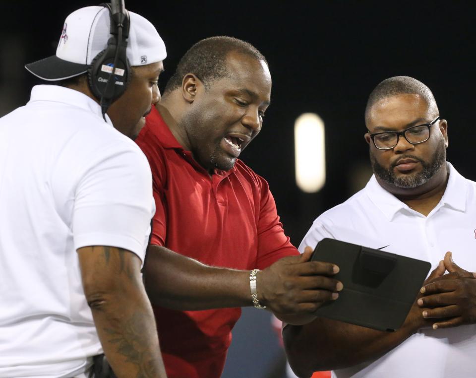 Former McKinley great Kenny Peterson (center) talks with his high school teammate DeMarlo Rozier (right) and Bulldogs assistant coach LaMar Sharpe (left) during McKinley's high school football game against Green at Tom Benson Hall of Fame Stadium on Sept. 17, 2021.