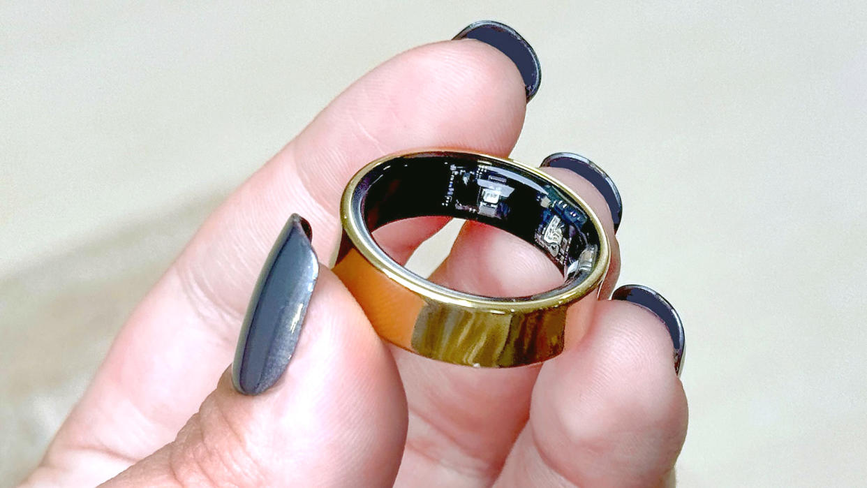  The Samsung Galaxy Ring in a user's hand with blue painted fingernails. 