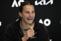 Aryna Sabalenka of Belarus holds up a glass of champagne at a press conference after defeating Elena Rybakina of Kazakhstan in the women's singles final at the Australian Open tennis championship in Melbourne, Australia, Saturday, Jan. 28, 2023. (AP Photo/Dita Alangkara)