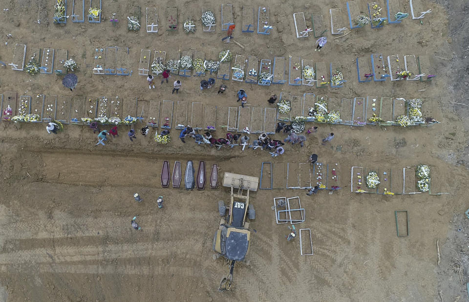 A backhoe buries coffins in a common pit at the Nossa Senhora Aparecida cemetery, amid the new coronavirus pandemic in Manaus, Amazonas state, Brazil, Wednesday, April 22, 2020. (AP Photo/Emerson Cardoso)