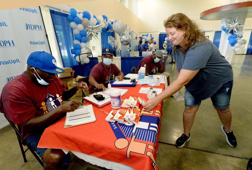 Jenny Bibly of Morris, Illinois, right, picks up some Self-Test At Home Covid-19 test kits from the Fifth Street Renaissance table that were supplied by the Illinois Department of Public Health Friday August 12, 2022 in the Illinois Building at this years Illinois State Fair.