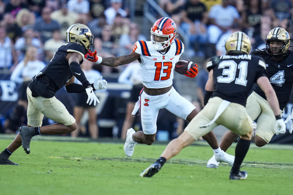 Illinois wide receiver Pat Bryant (13) tries to hold off the tackle of Purdue defensive back Markevious Brown (1) during the second half of an NCAA college football game in West Lafayette, Ind., Saturday, Sept. 30, 2023. (AP Photo/Michael Conroy)