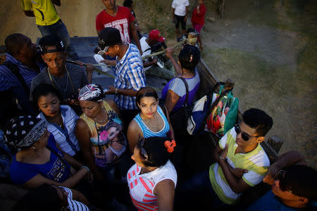 People stand in the back of a truck as they wait to be taken to the recording of an episode of the popular TV show "Palmas y Canas" in the village of Cerrito de Naua, in the Sierra Maestra, Cuba, March 30, 2018. REUTERS/Alexandre Meneghini