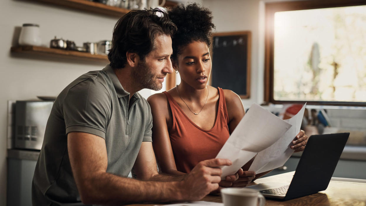 Cropped shot of an affectionate young couple going through paperwork while doing their budget at home.