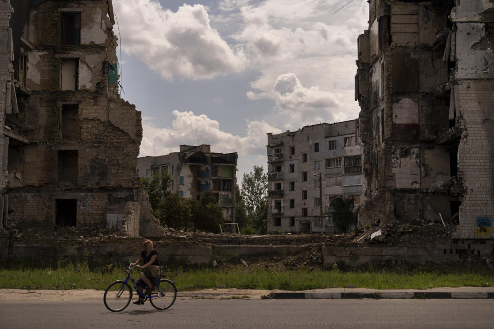 A woman rides her bike past an apartment building destroyed in Russian attacks in Borodyanka, Ukraine, Wednesday, Aug. 2, 2023. Borodyanka was occupied by Russian troops at the beginning of their full-scale invasion last year. (AP Photo/Jae C. Hong)