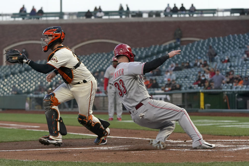 Cincinnati Reds' Jesse Winker (33) slides home to score past San Francisco Giants catcher Buster Posey during the second inning of a baseball game in San Francisco, Tuesday, April 13, 2021. (AP Photo/Jeff Chiu)