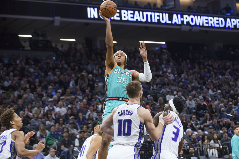 San Antonio Spurs guard Romeo Langford (35) lays the ball up over Sacramento Kings forward Domantas Sabonis (10) during the first quarter of an NBA basketball game in Sacramento, Calif., Sunday, April 2, 2023. (AP Photo/Randall Benton)