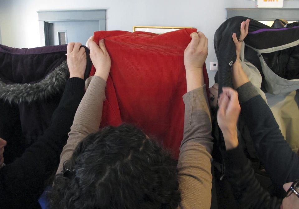 People hold up coats to block harasser Max Misch from view at Monday's press conference. (Photo: ASSOCIATED PRESS)