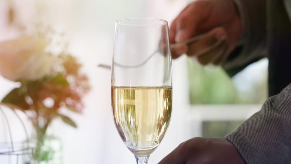 Close-up of a person's hand holding a half-full champagne flute