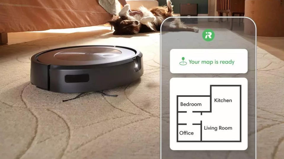 Imagem do produto do iRobot Roomba j9+. O robô se move ao longo de um tapete com um cachorro ao fundo. Aplicativo de smartphone sobreposto mostrando suas habilidades de mapeamento.