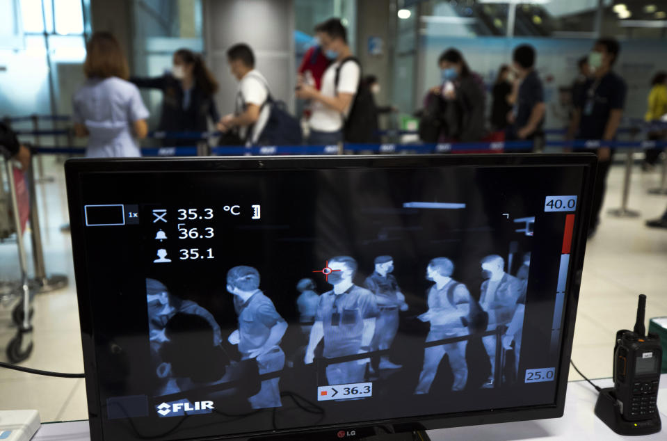 Tourists walk in front of a thermal scanner to check body temperatures as they arrive at the Suvarnabhumi Airport in Bangkok, Thailand, March 4, 2020. (AP Photo/Sakchai Lalit)