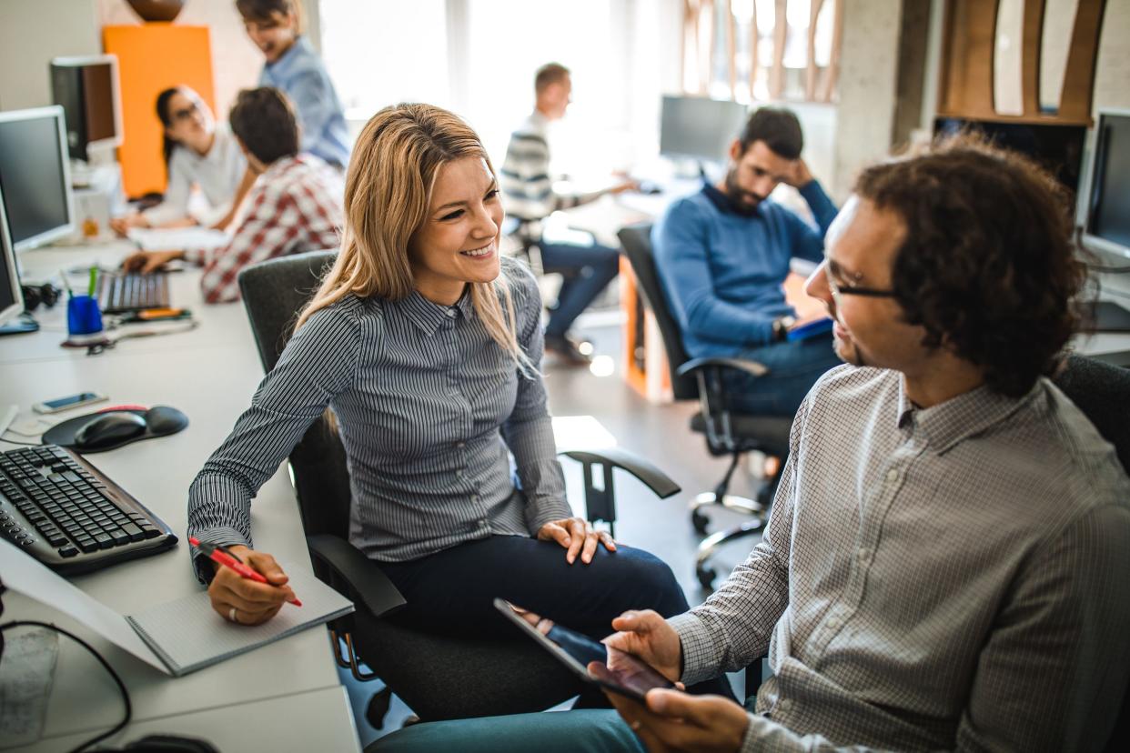 happy computer programmers talking while cooperating in the office