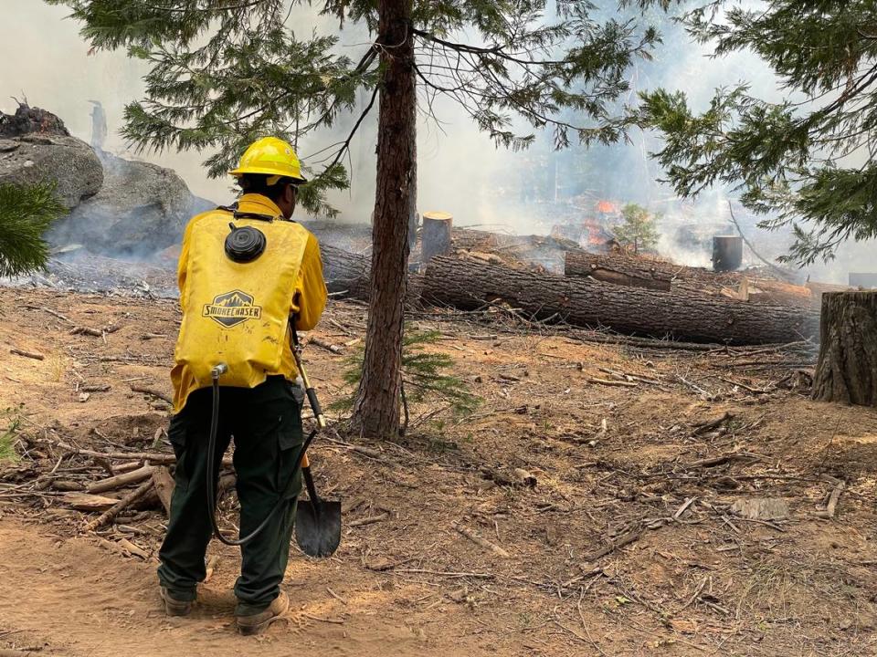 A fire technician with the Sierra-Sequoia Burn Cooperative watches forest debris burn during a prescribed fire set in October 2023 on private property near Dinkey Creek east of Fresno, California. The group is a partnership between four Native American Tribes, the Sierra Foothill Conservancy, UC Cooperative Extension, several private landowners, fire practitioners, and local researchers.