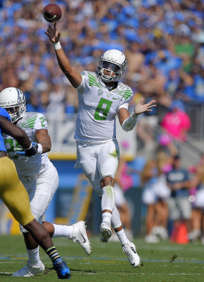 FILE - In this Oct. 11, 2014, file photo, Oregon quarterback Marcus Mariota passes during the first half of an NCAA college football game against UCLA in Pasadena, Calif. The College Football Playoff participants are well represented on The Associated Press All-America team. Heisman winner Marcus Mariota is the first Ducks&#39; quarterback to be an All-American. (AP Photo/Mark J. Terrill, File)