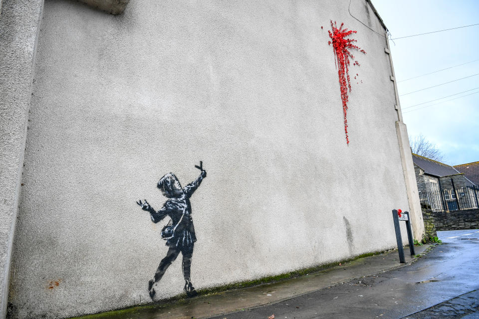 L'ultima creazione dello street artist britannico sulla facciata di un edificio a Bristol, sua città natale in Inghilterra: una bambina con una fionda di fronte a un’esplosione rossa, fatta di petali e fiori di plastica, forse il cuore infranto di Cupido. (Photo by Ben Birchall/PA Images via Getty Images)