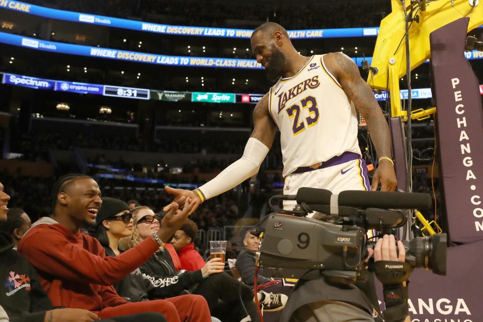 Lakers forward LeBron James shakes hands with his son Bronny James during the second half against the Houston Rockets, Nov. 19, 2023, in Los Angeles.